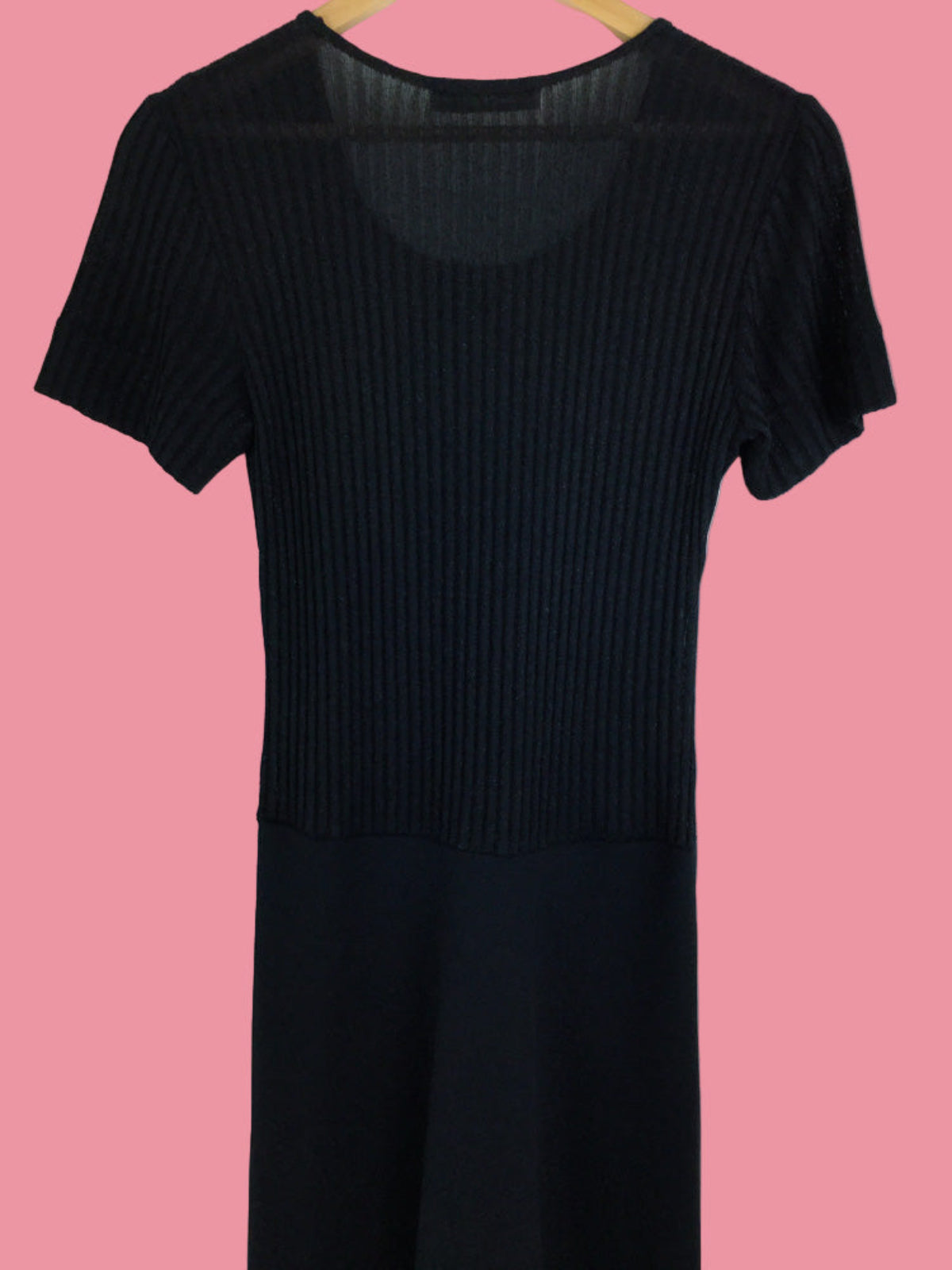 Black ribbed dress on a hanger against a pink background