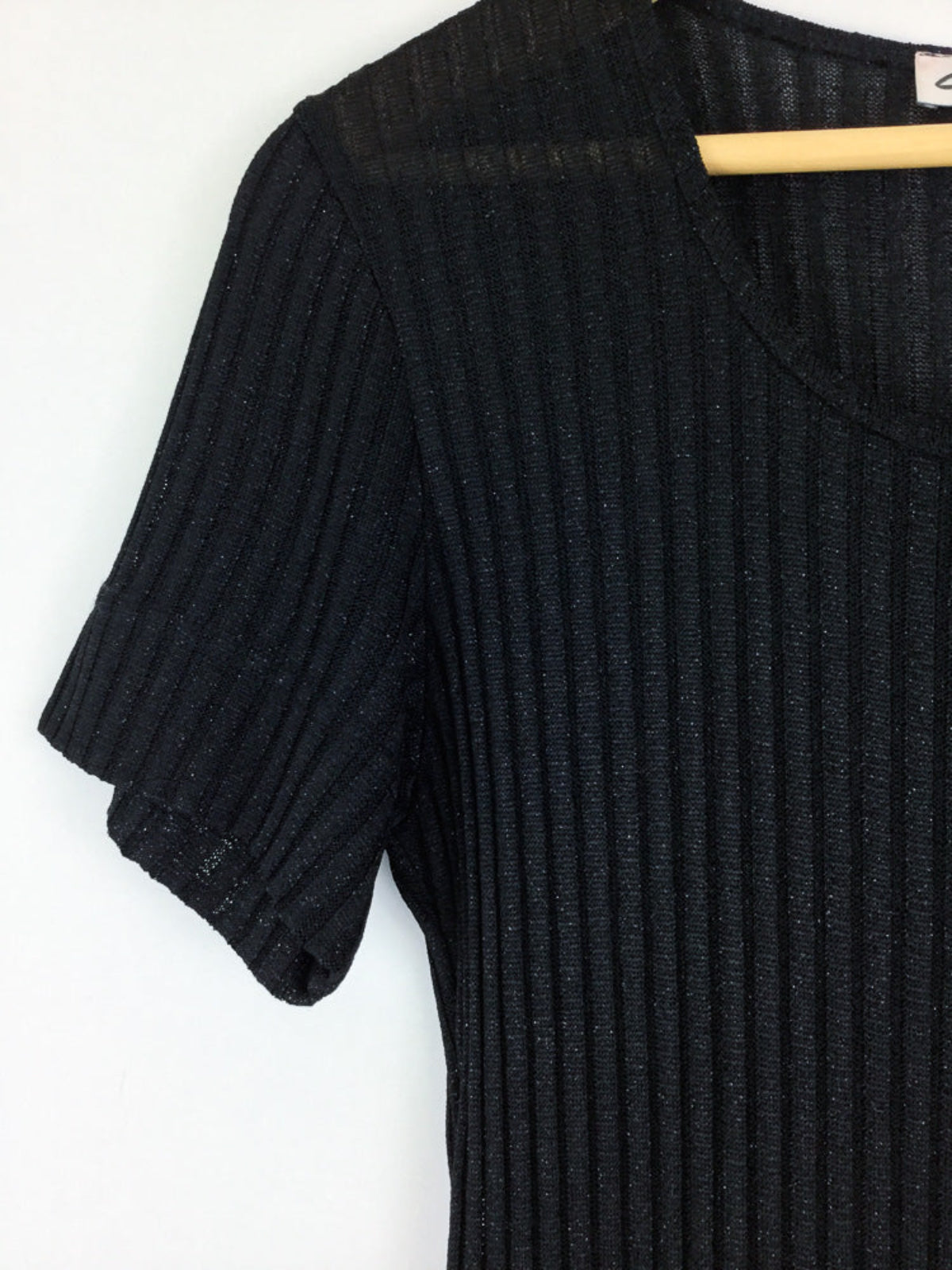 Black ribbed dress on a hanger against a white background