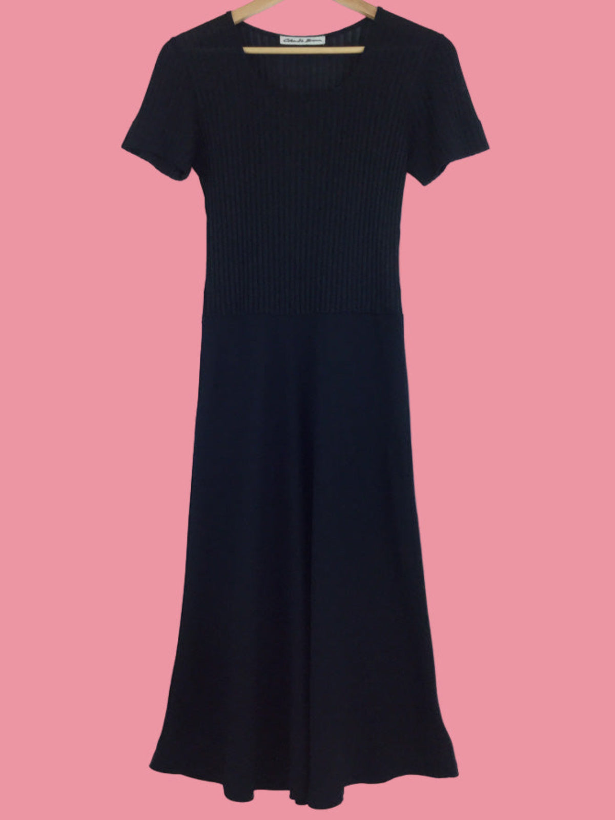 Black dress on a hanger against a pink background