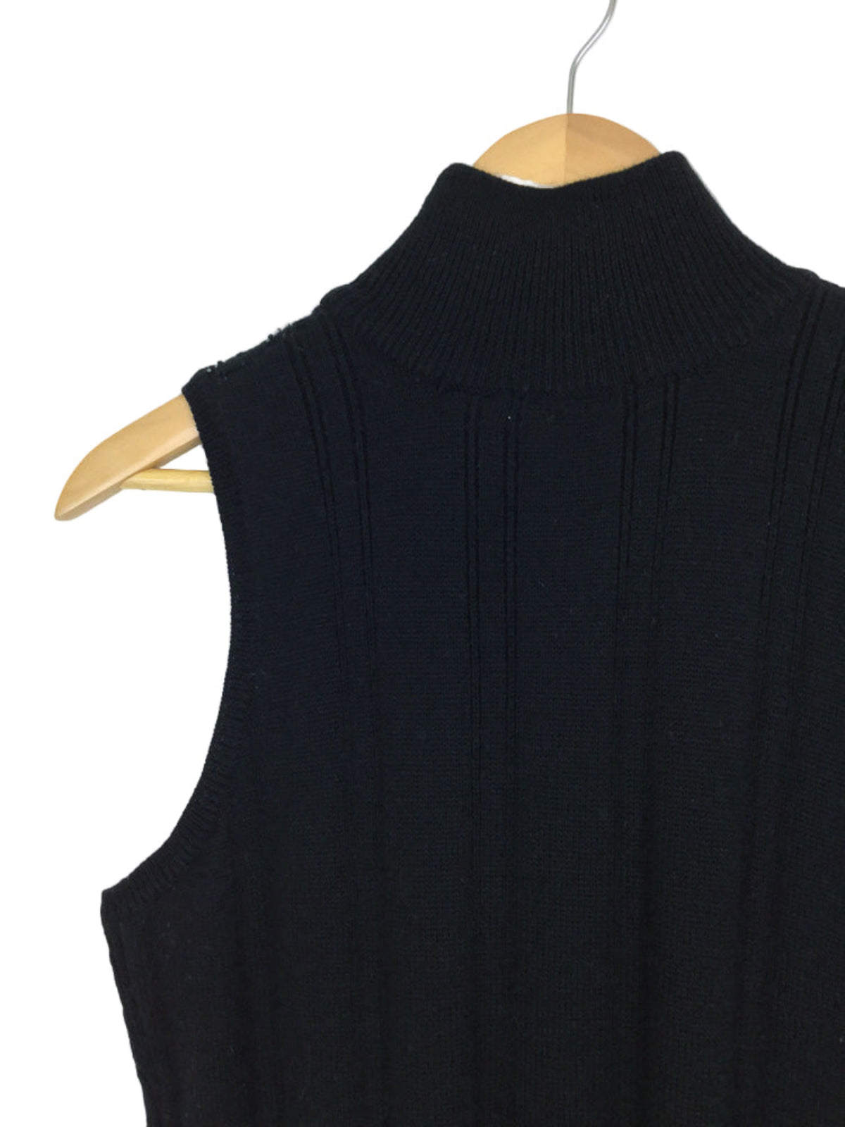 Black sleeveless sweater vest on a wooden hanger against a white background