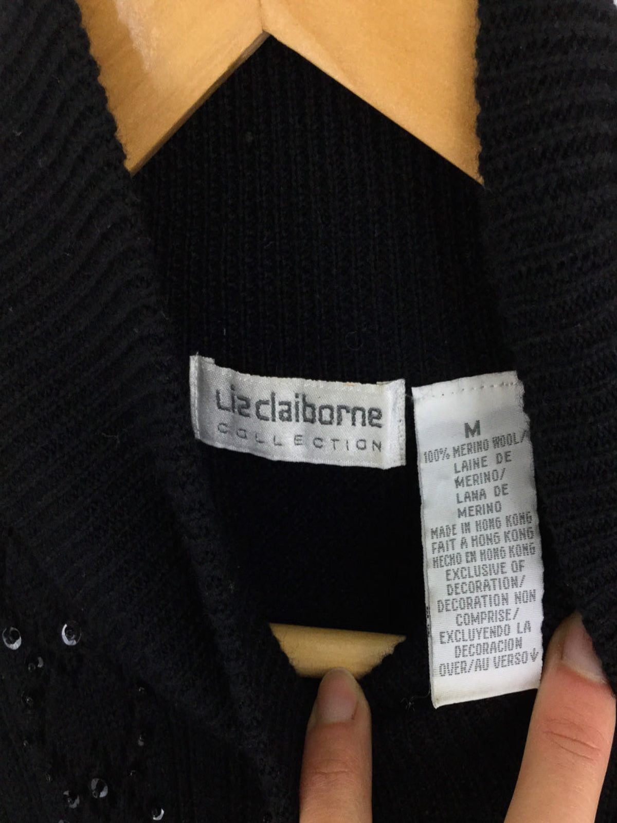 Close-up of a Liz Claiborne label on a garment with a hand pointing to it.
