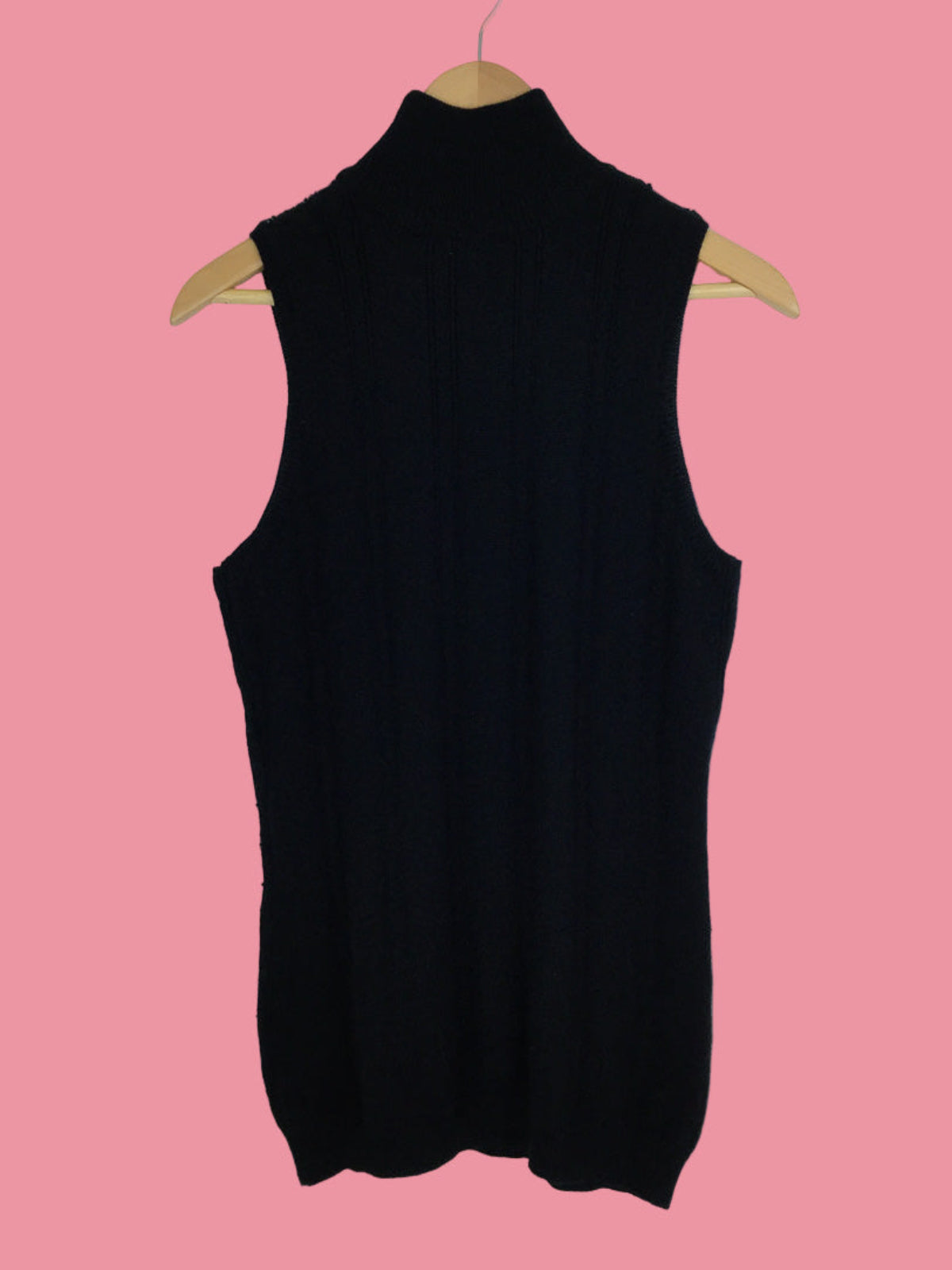 Black sleeveless top on a wooden hanger against a pink background