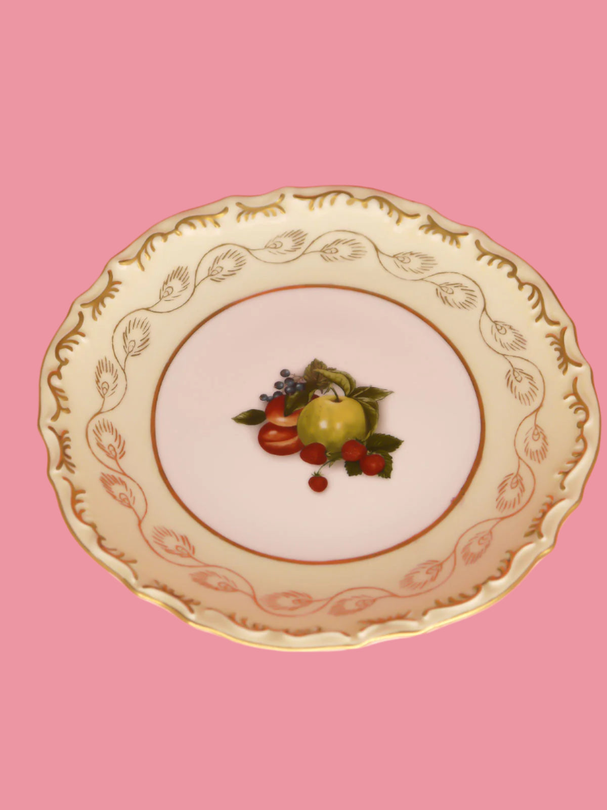 Vintage Dianti decorative plate with fruit in the centre on a white background with gold edging and gold patterns around the rim