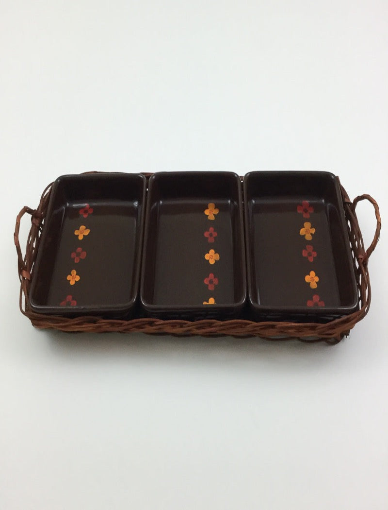 Vintage 70's brown stoneware three serving platters nestled in a brown woven basket with two handles. Serving platters have five hand painted flowers.