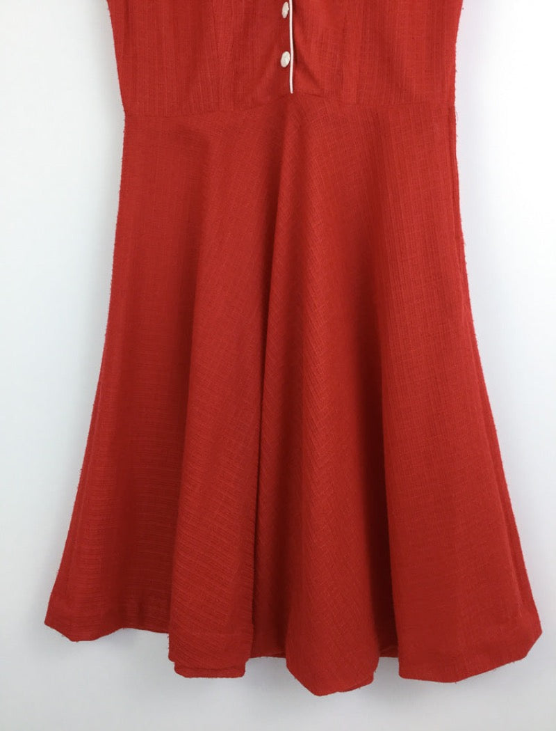 1970's red v-neck sleeveless sheer a-line dress with white piping around the arms and neckline with white buttons down the front