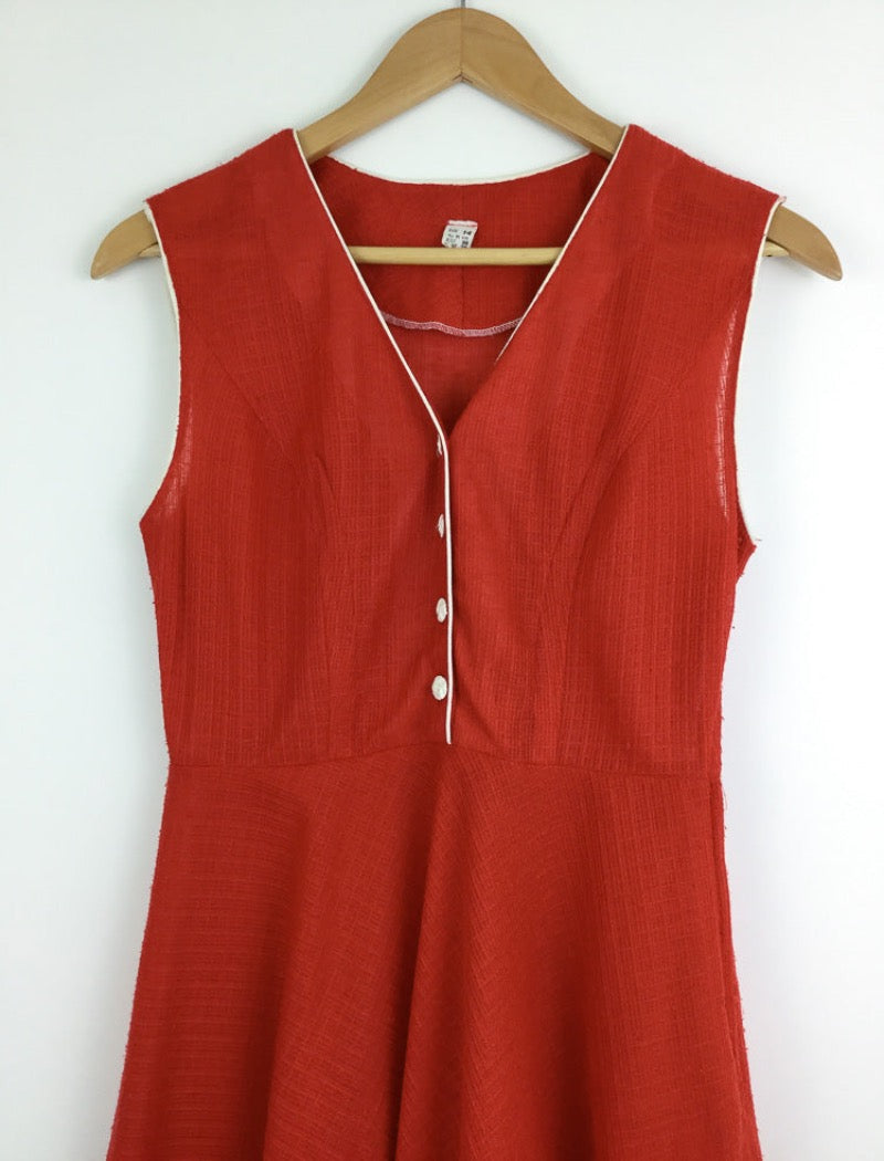 1970's red v-neck sleeveless sheer a-line dress with white piping around the arms and neckline with white buttons down the front