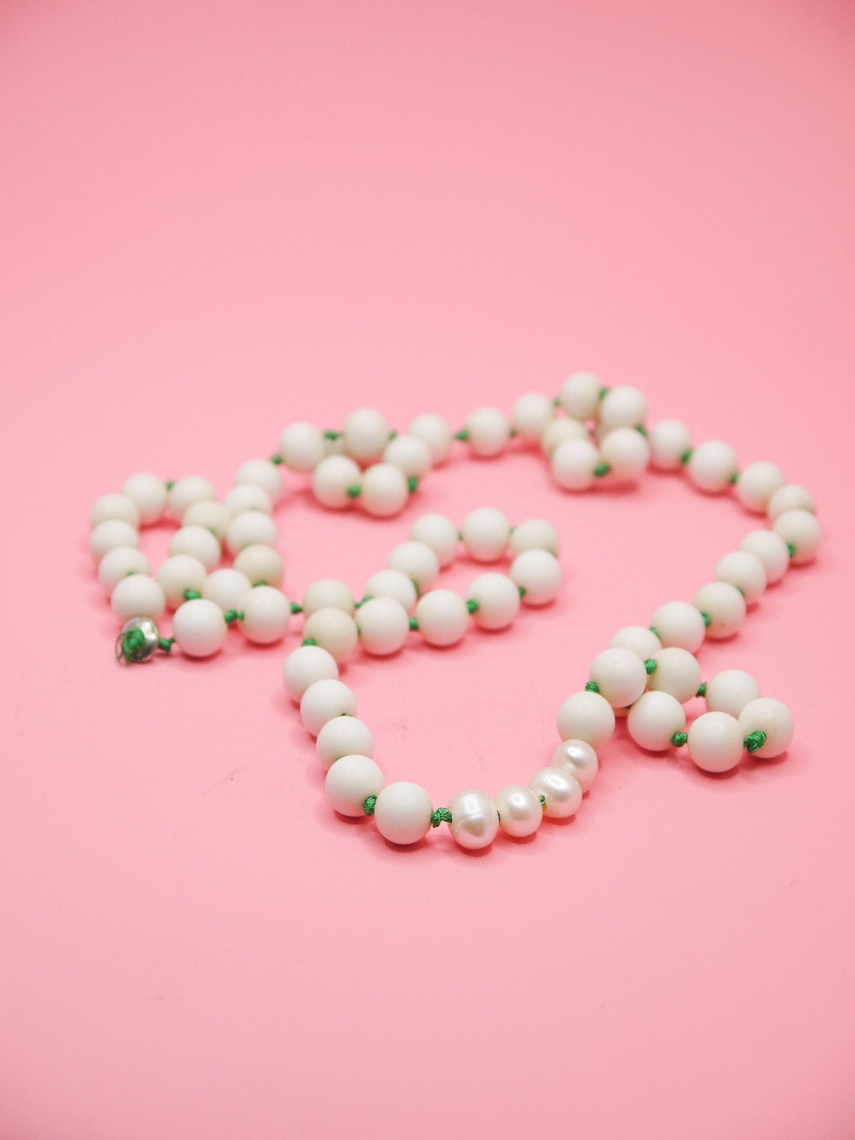 White bead necklace with green silk knots between each bead and four mother of pearl feature beads in a row.