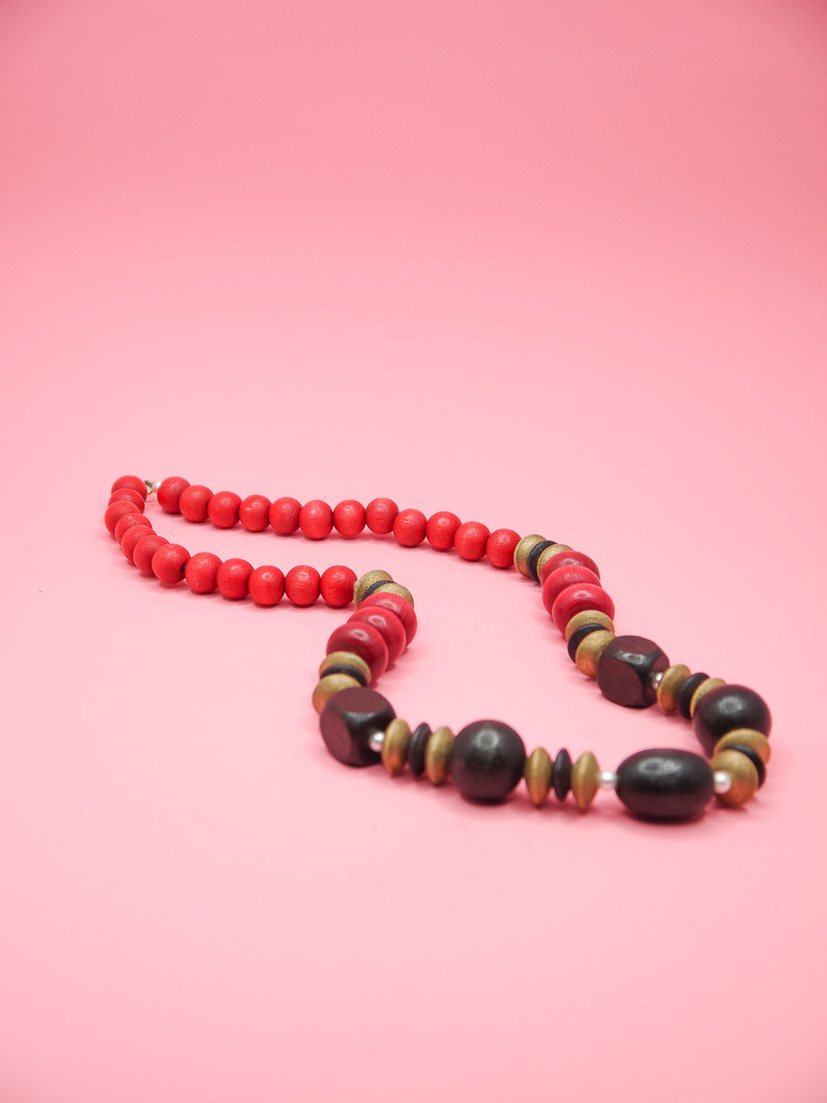 Chunky wooden bead necklace in various shapes and sizes in browns and reds with tiny pearl spacer beads and a clasp closure.