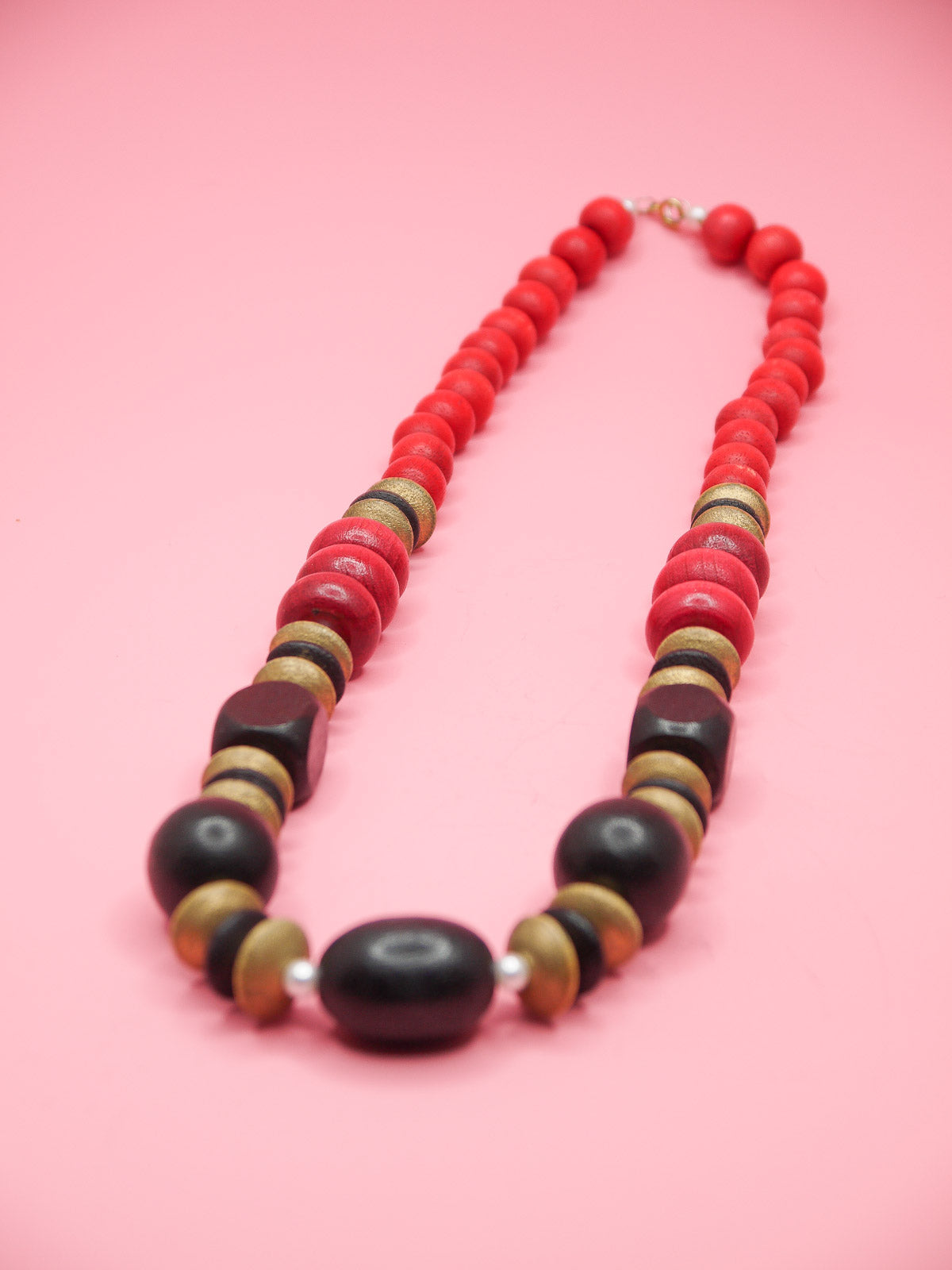 Chunky wooden bead necklace in various shapes and sizes in browns and reds with tiny pearl spacer beads and a clasp closure.